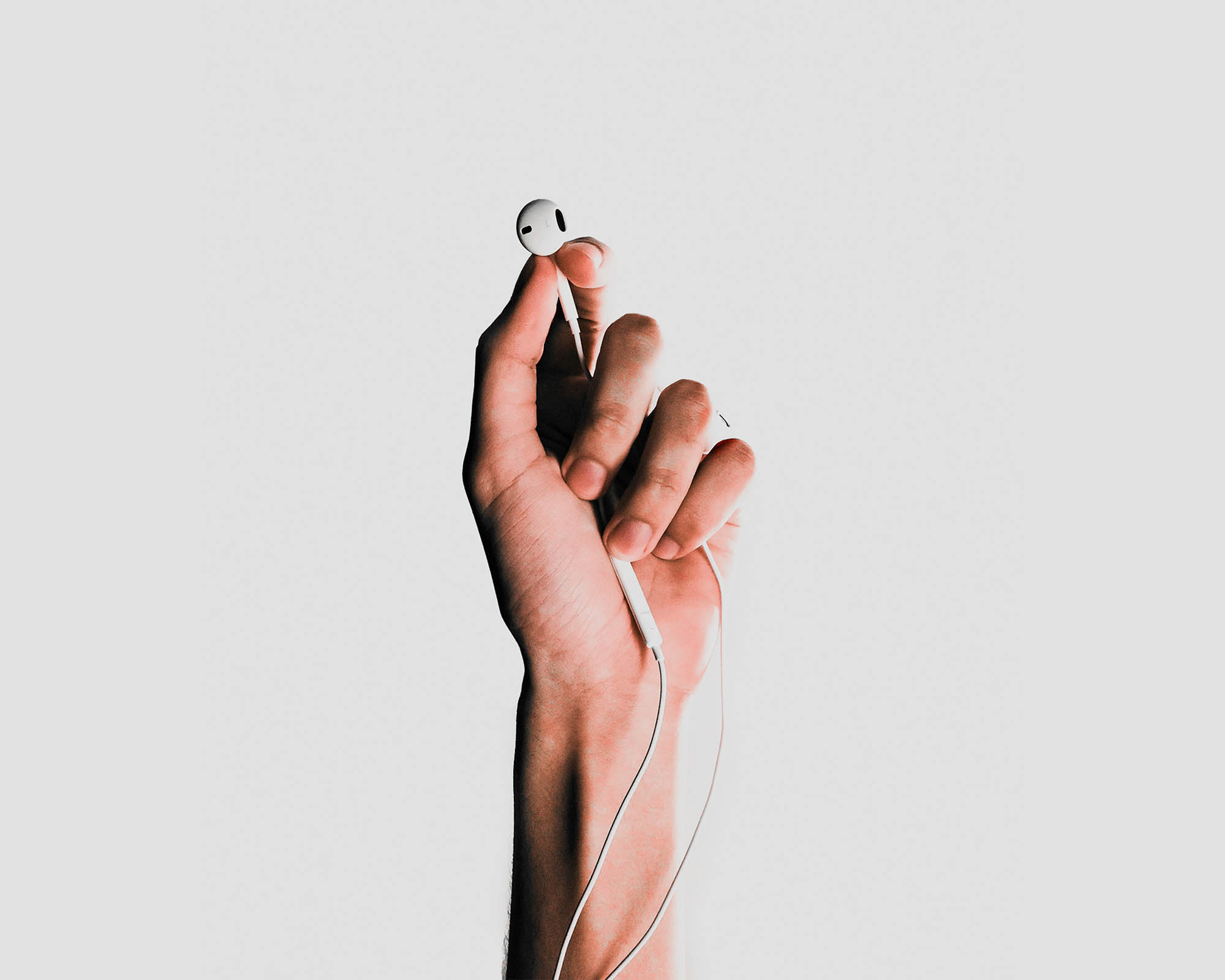 hand holding headphones on grey background listening to ethical fashion podcast