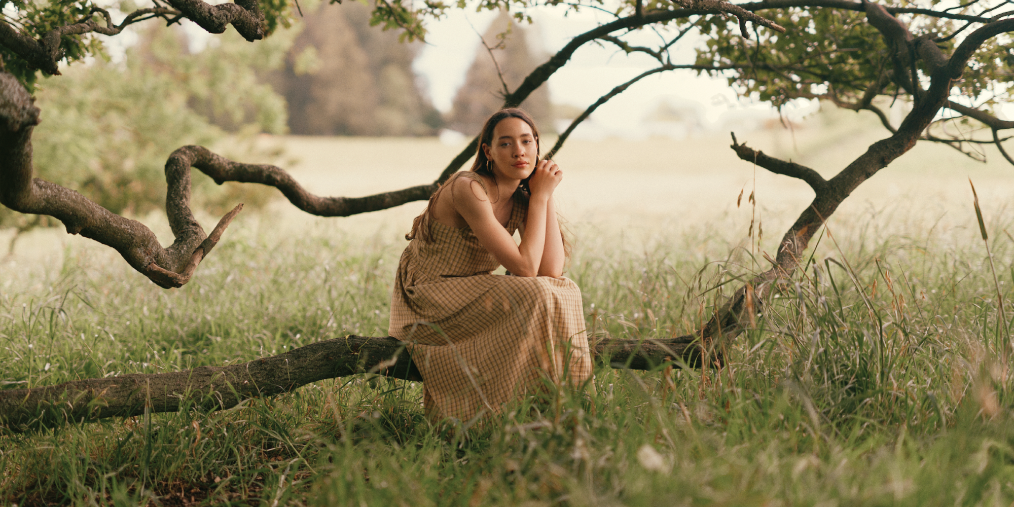 Someone sitting in a tree wearing a dress by more responsible brand, ReCreate.