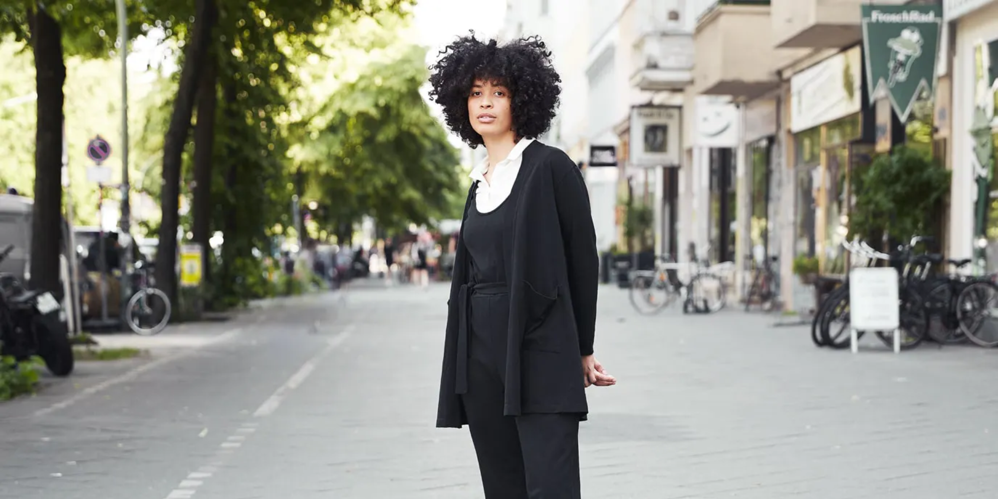 Someone wearing a white collared shirt, a black jumpsuit, and cardigan by Dorsu.