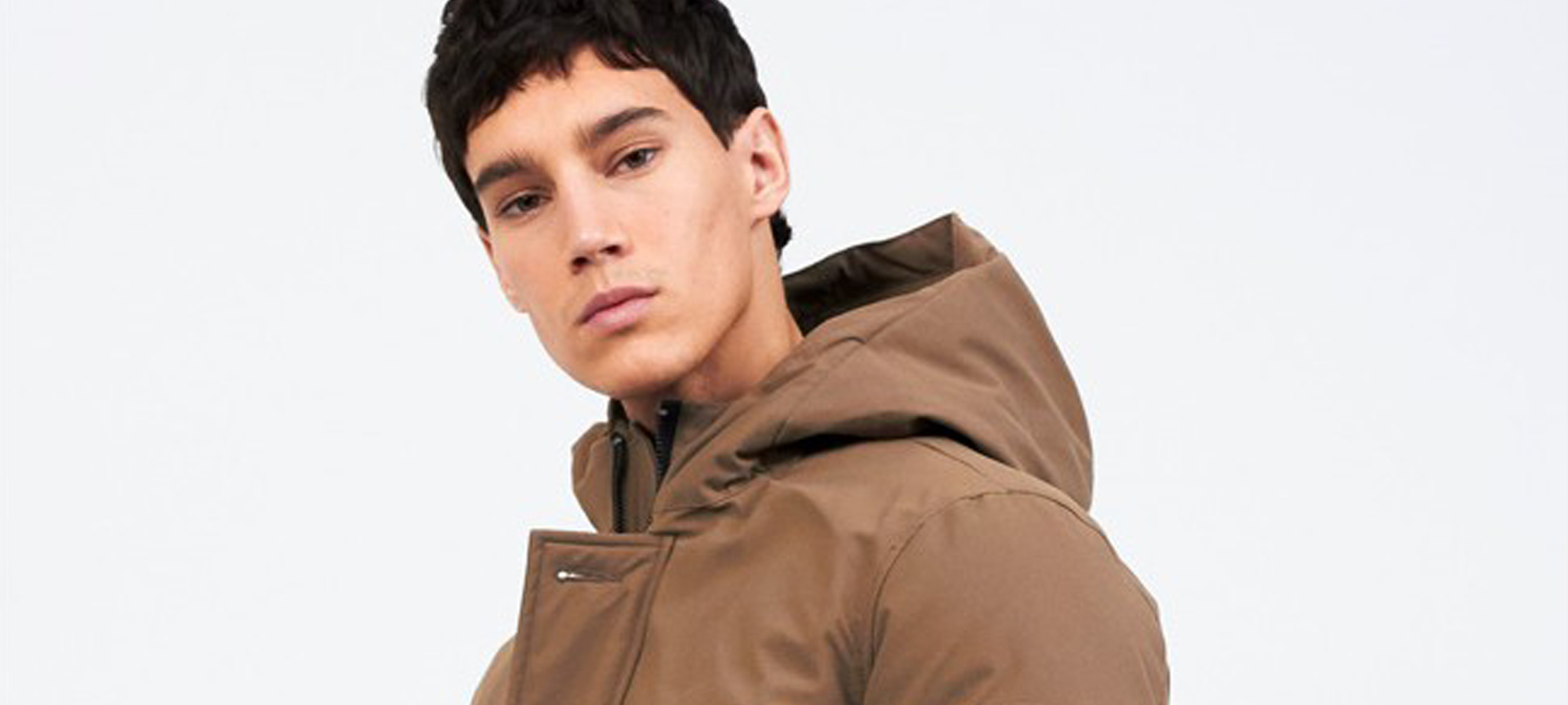 A man with a tan-coloured hooded coat looks at the camera.