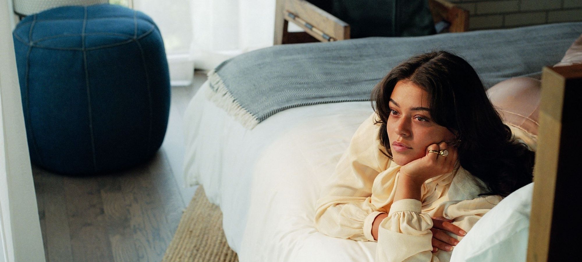 woman lying on bed wearing Raven + Lily jewellery and homewares