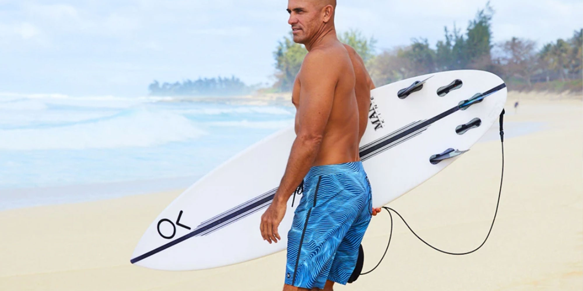 Kelly Slater wearing blue Outerknown surf trunks.