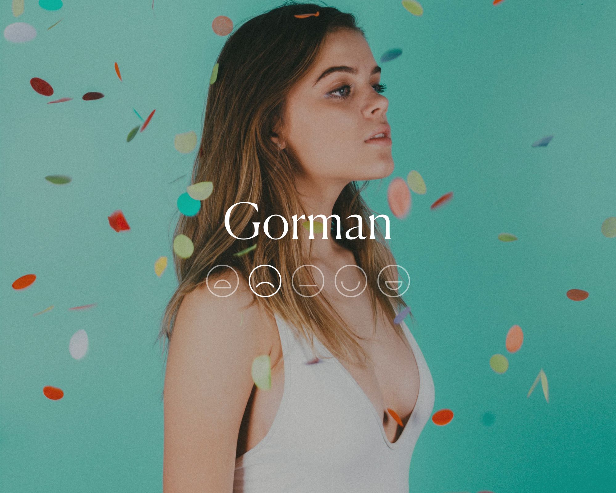 Someone wearing a white dress standing in rainbow confetti with the word Gorman and a sad emoji face overlaid in white text.