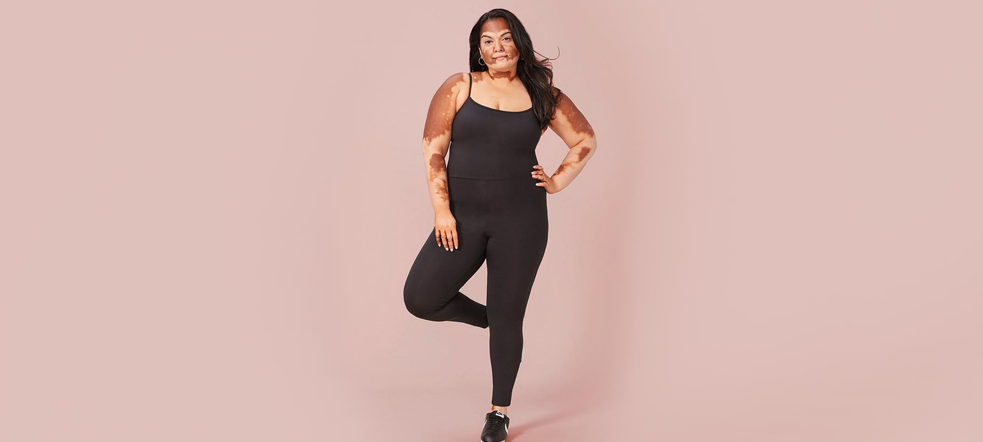 plus size woman with vitiligo wearing recycled plastic black unitard by ethical fashion brand Girlfriend Collective