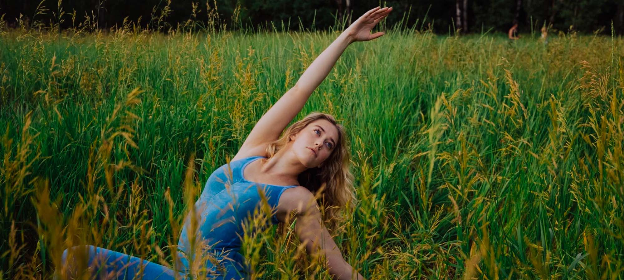 woman in field of grass wearing ethical blue Purusha People unitard