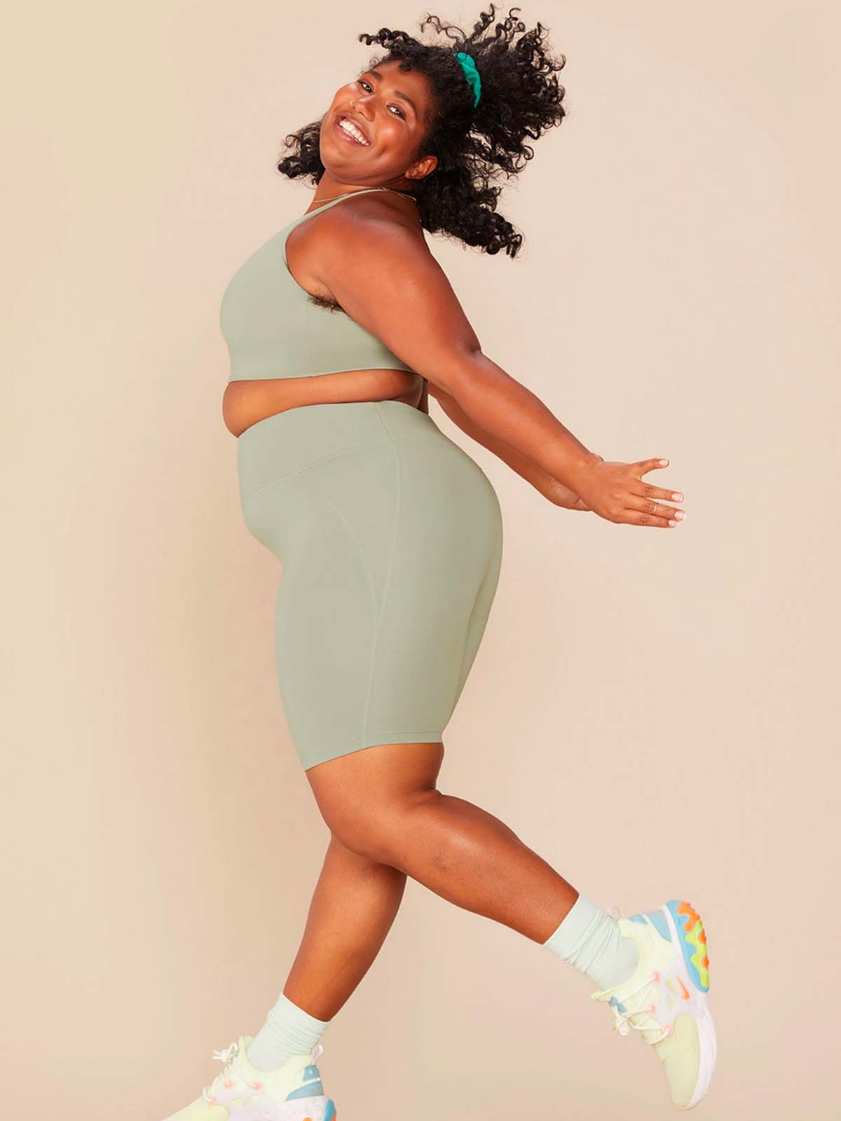 plus size woman of colour happy in light green recycled plastic yoga wear