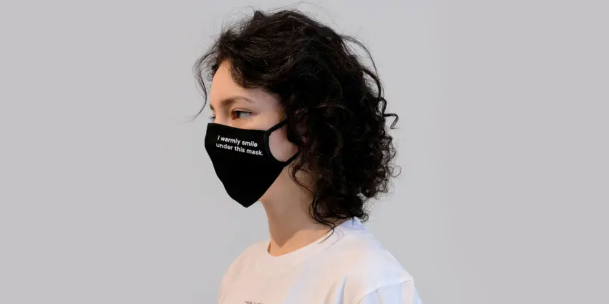 woman wearing black slogan face mask by ethical brand Armedangels