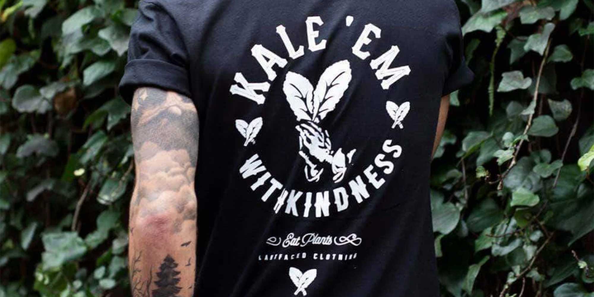 man wearing black kale em with kindness plant faced t-shirt