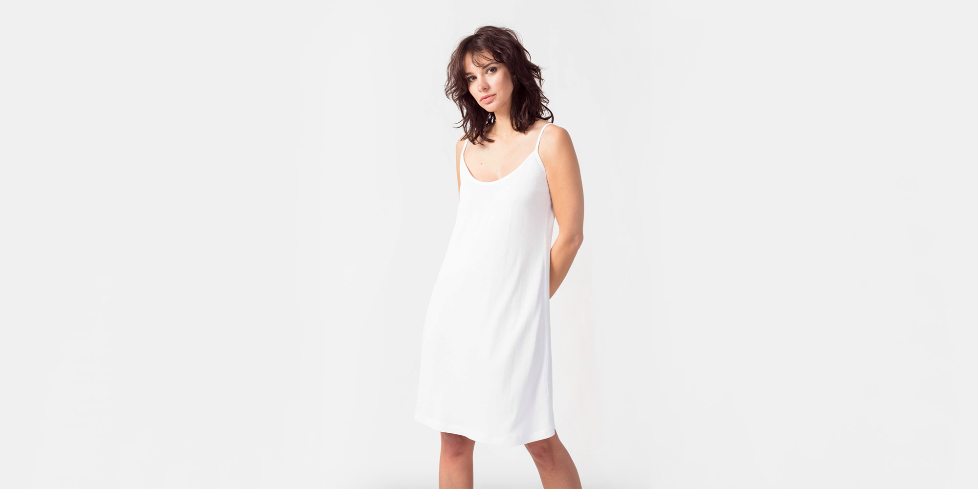 woman wearing white sustainable slip dress by SKFK