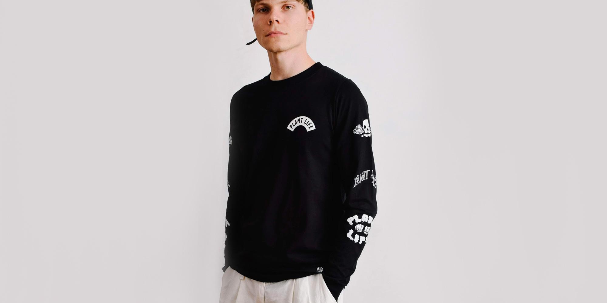 man wearing black vegan long sleeve t-shirt by plant faced