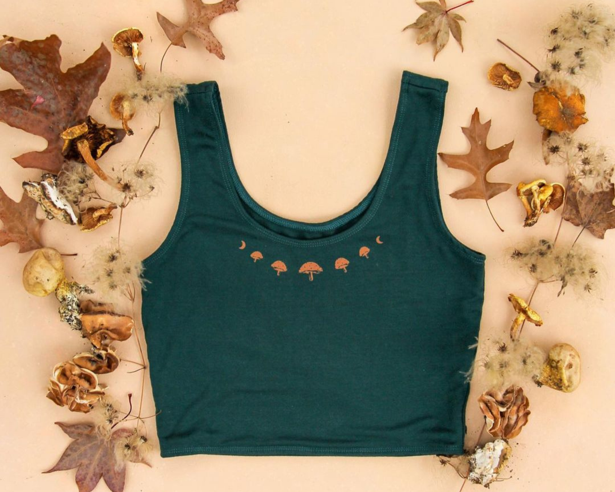 green natural yoga top with gold mushroom detailing surrouned by autumn leaves by ethical activewear brand Purusha People
