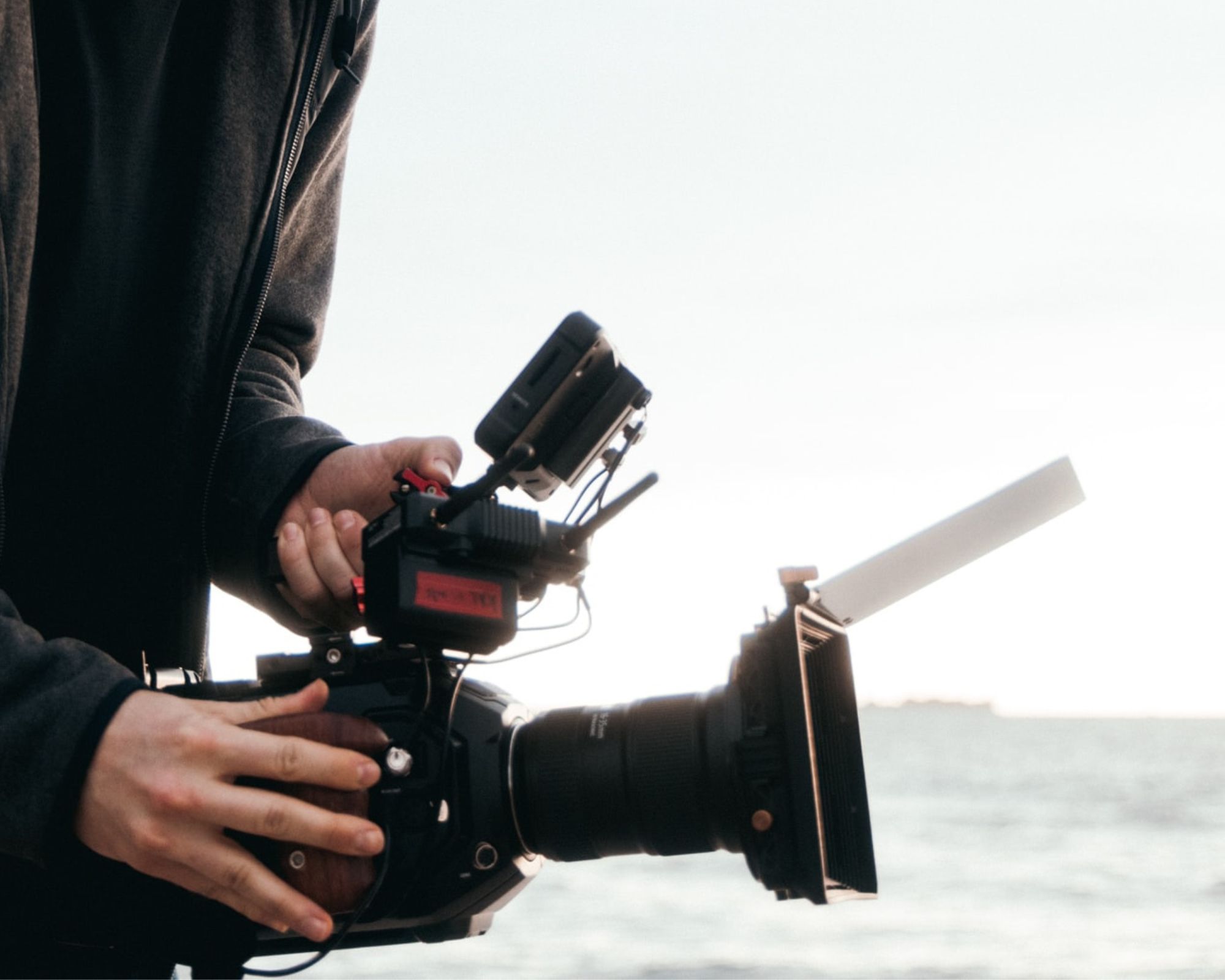 A documentary camera being held above an ocean background.
