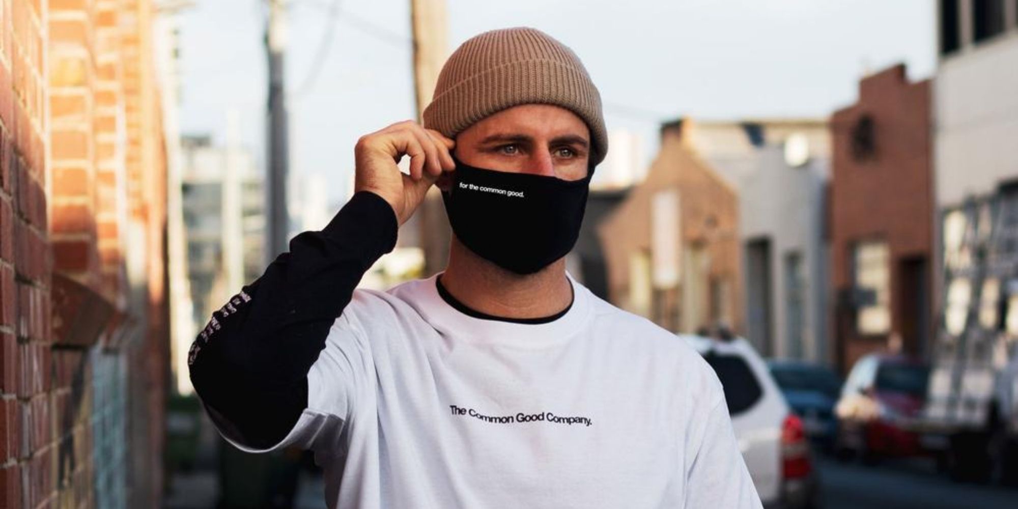man wearing For The Common Good logo black face mask by The Common Good Company