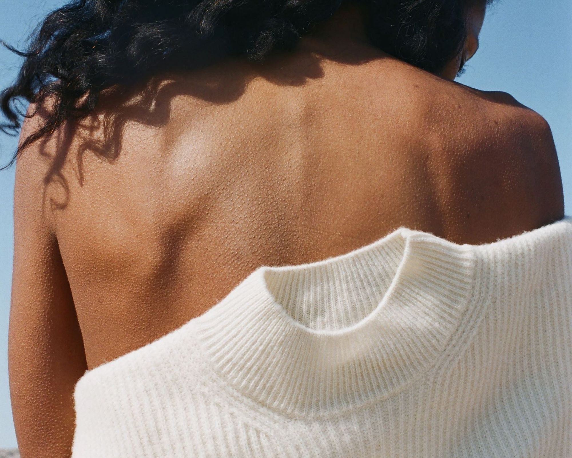 sustainable white ASKET jumper against a woman's bare back