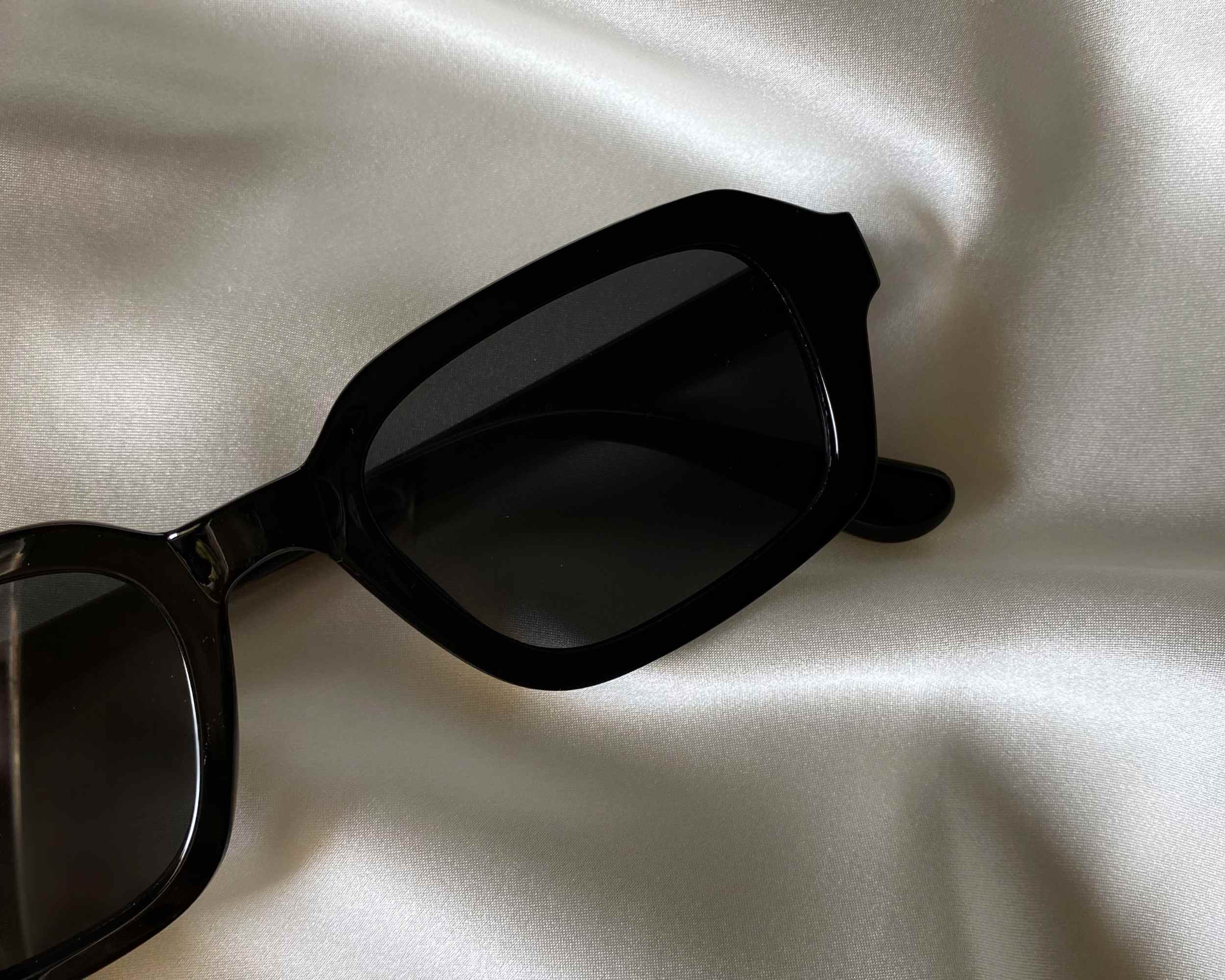 Sunglasses on shiny fabric