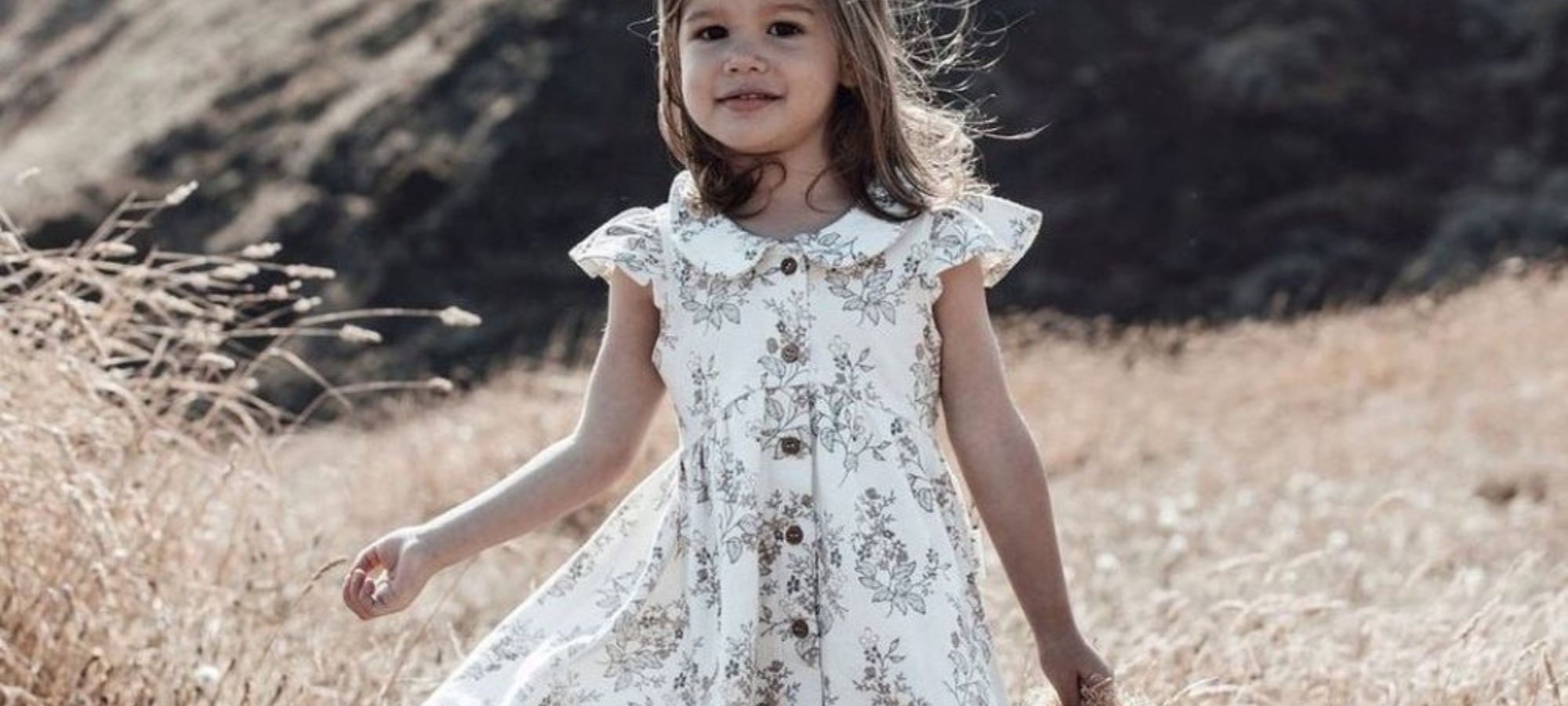 baby girl wearing black and white floral print sustainable dress by Aster & Oak
