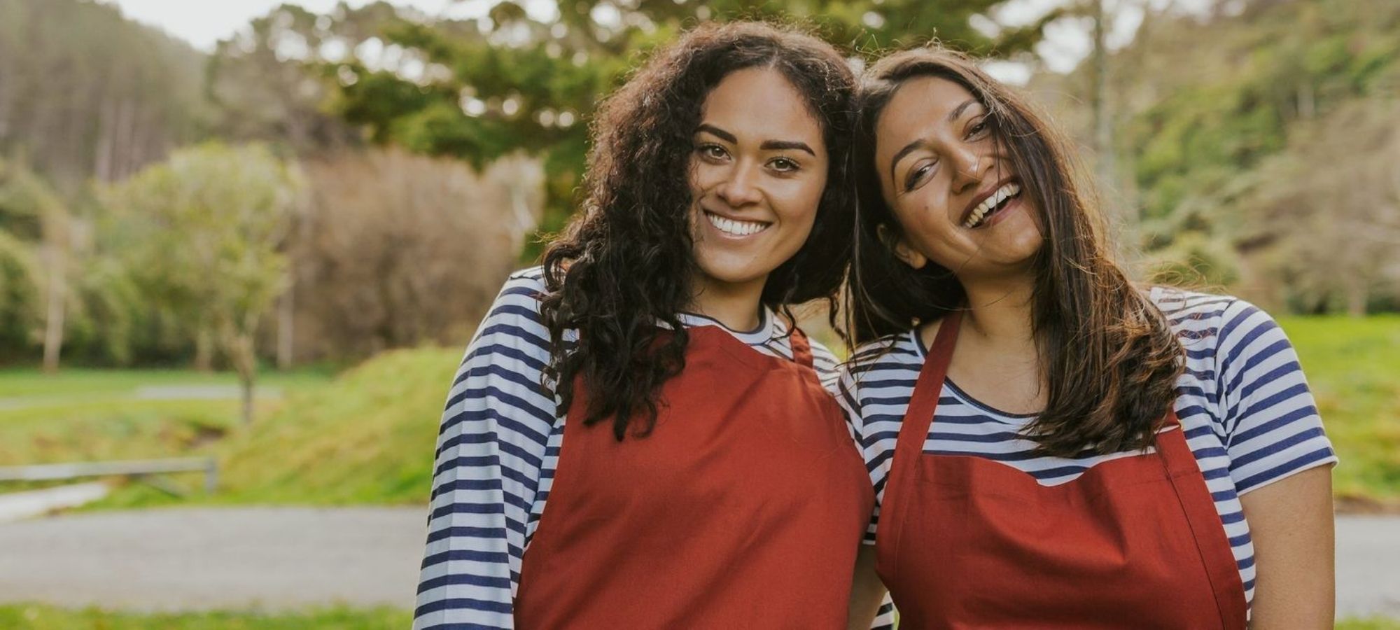 two women wearing blue and white striped tops under red overalls by ethical brand Little Yellow Bird