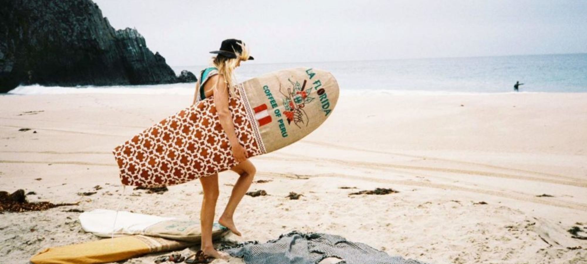 woman carrying surfboard in colourful upcycled surfbag by Sagebrush Surf Bags