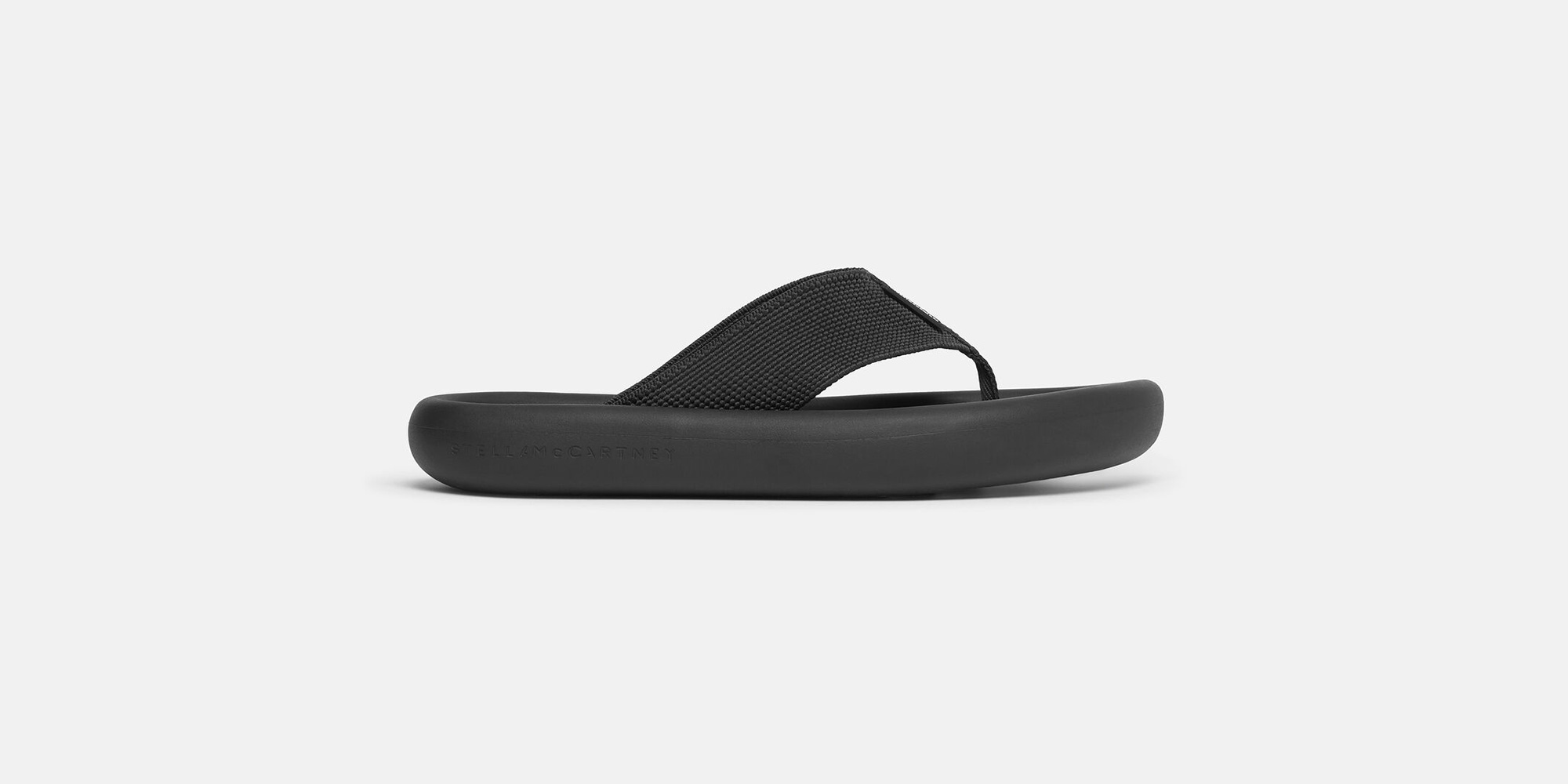 Side view of black platform sustainable flip flops by Stella McCartney.