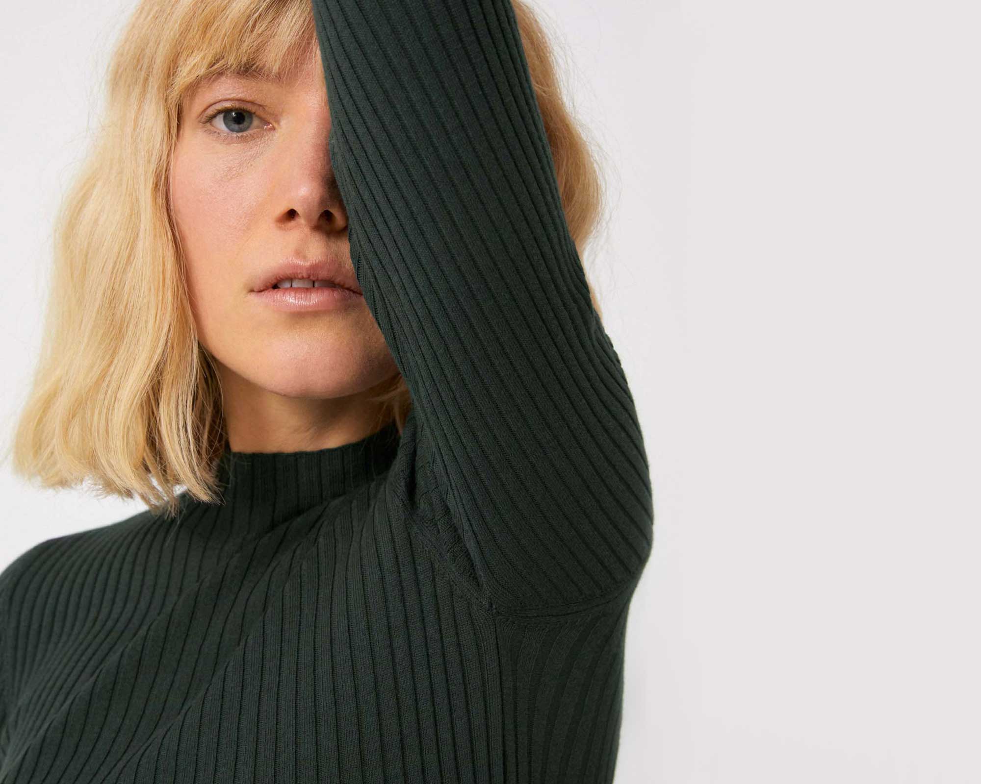 blonde woman wearing forest green sustainable fall staples turtleneck by Armedangels