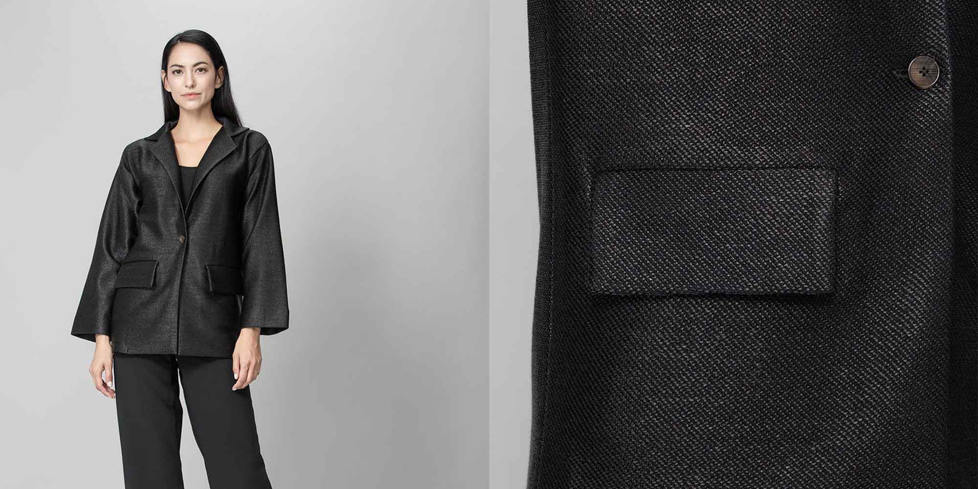 Someone wearing a black upcycled viscose coat by The R Collective.