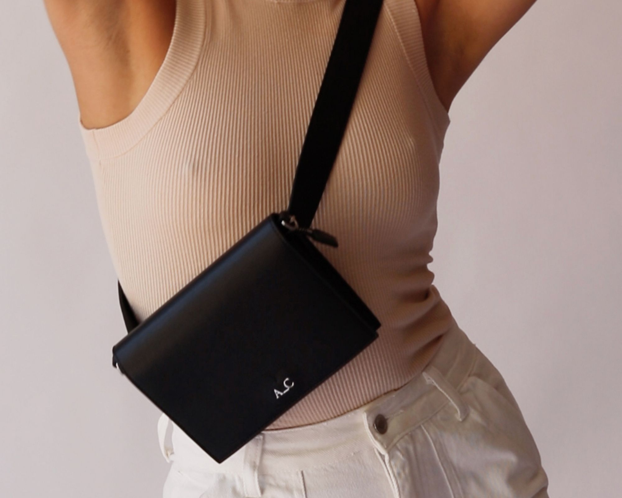 Cropped shot of someone holding up their arms and wearing a black crossbody vegan bag ethically made by A_C.