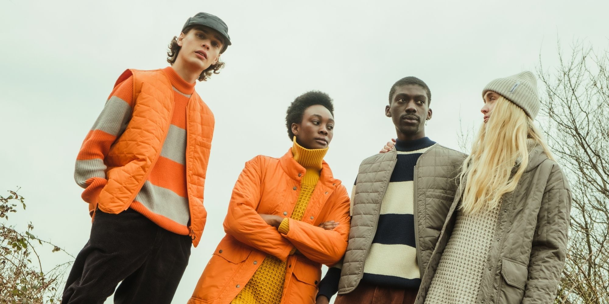 Four people are wearing sustainable knit and outwear by Dedicated in tones or orange and grey.