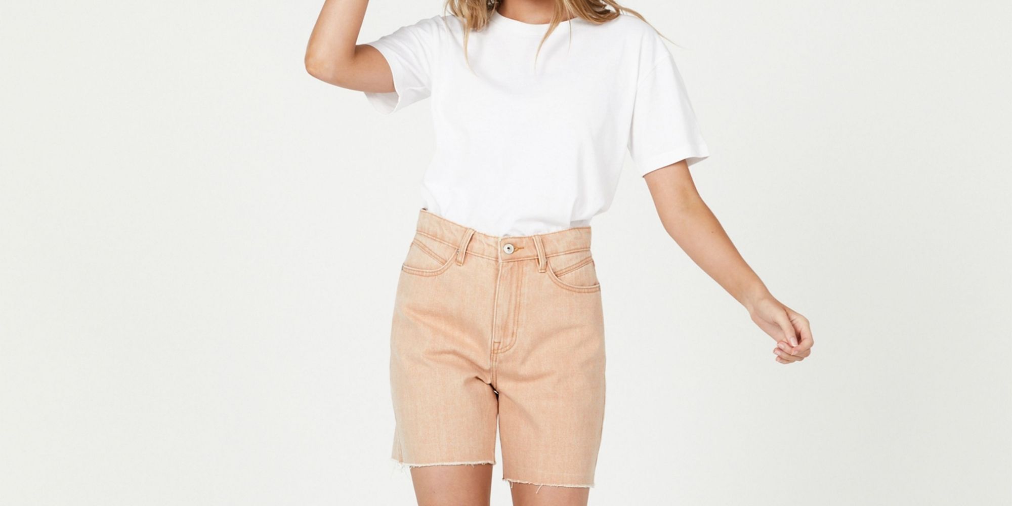 Cropped studio shot of someone wearing a white tshirt and light peach naturally clay dyed denim shorts by Outland Denim.