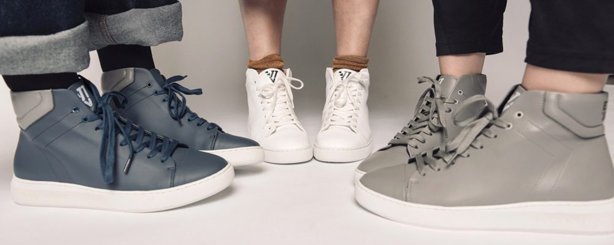 Cropped shot of three people wearing a blue, white, and grey pair of sustainable sneakers by Ella Witt.