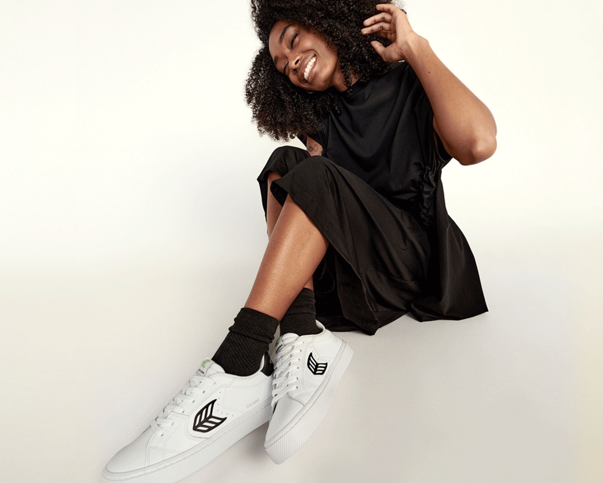 Someone smiling wearing black and white cleaner leather Salvas sneakers by CARIUMA.