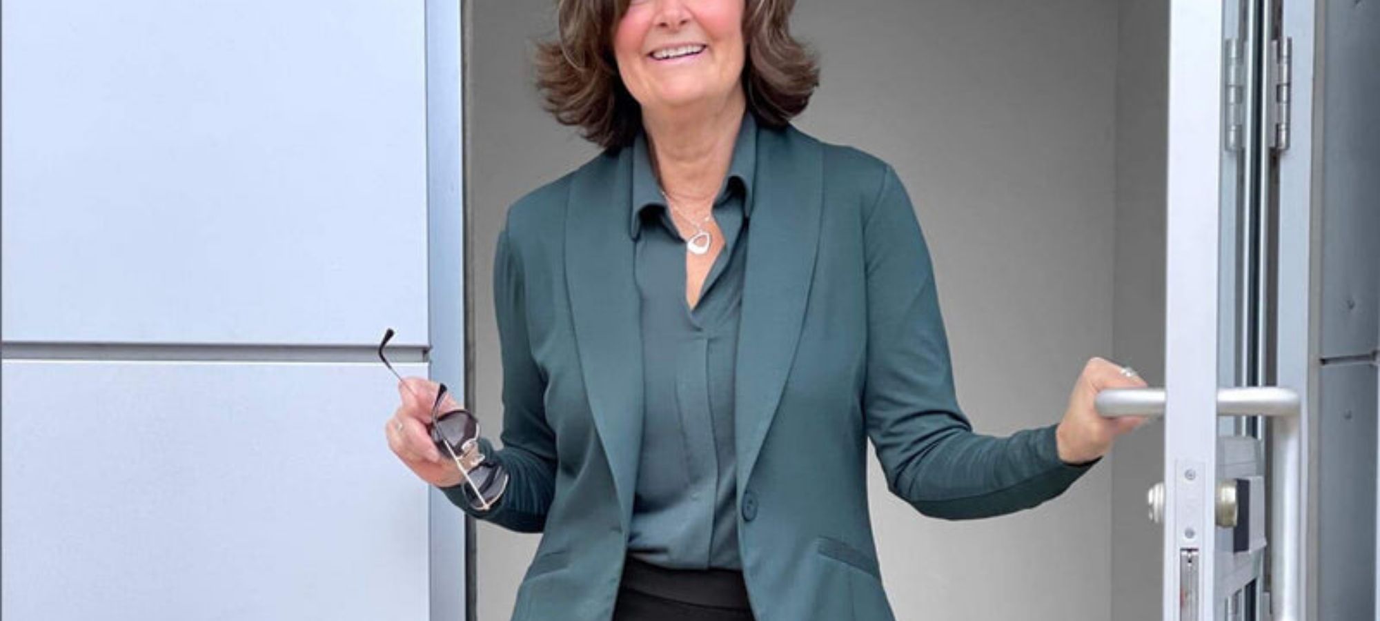 An older person wearing a teal soft blazer ethically made by MiiK.