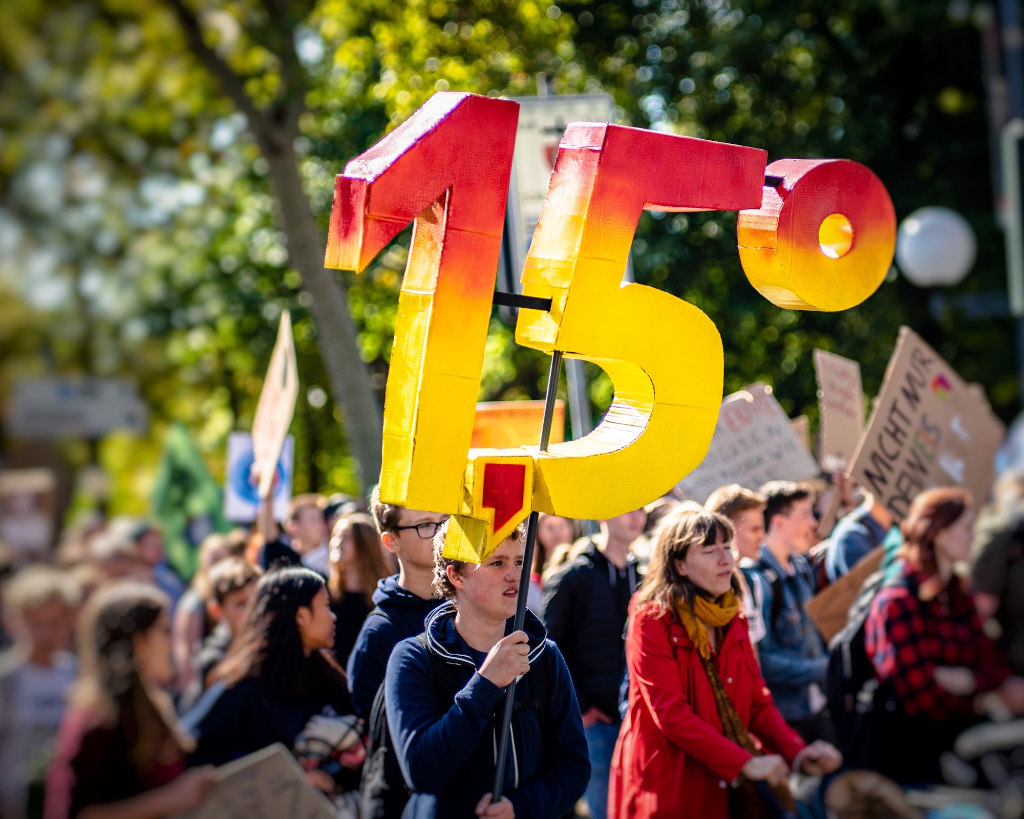 Protestor stands in a crowd at a climate demonstration holding up the number 1.5 degrees