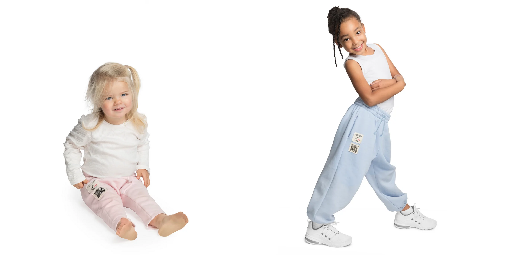 toddler sitting in white long-sleeved top and pink pants, and kid in white sleeveless top and light blue sweatpants by Katla