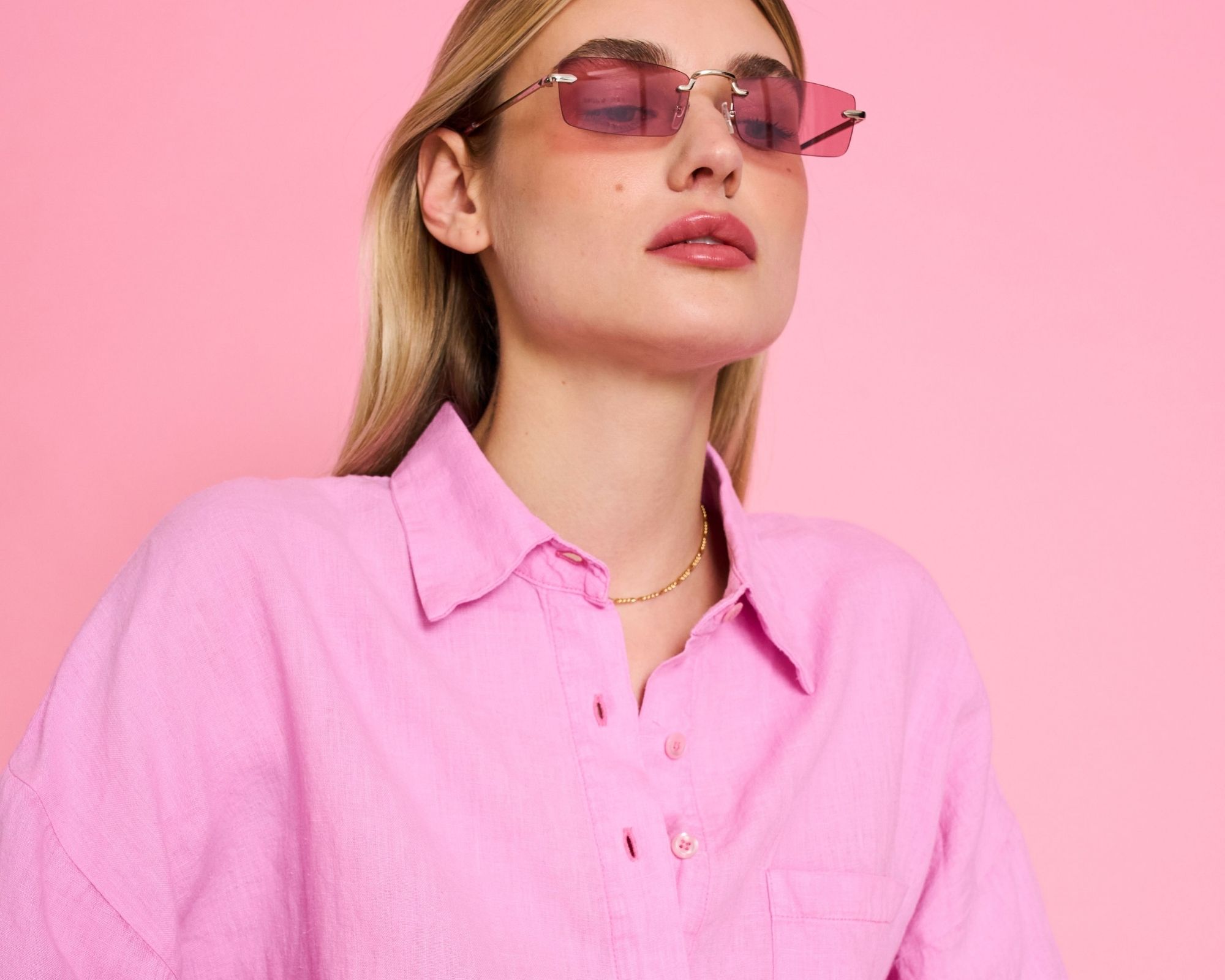 Someone wearing pink sunglasses and a pink linen shirt by JAN 'N JUNE.
