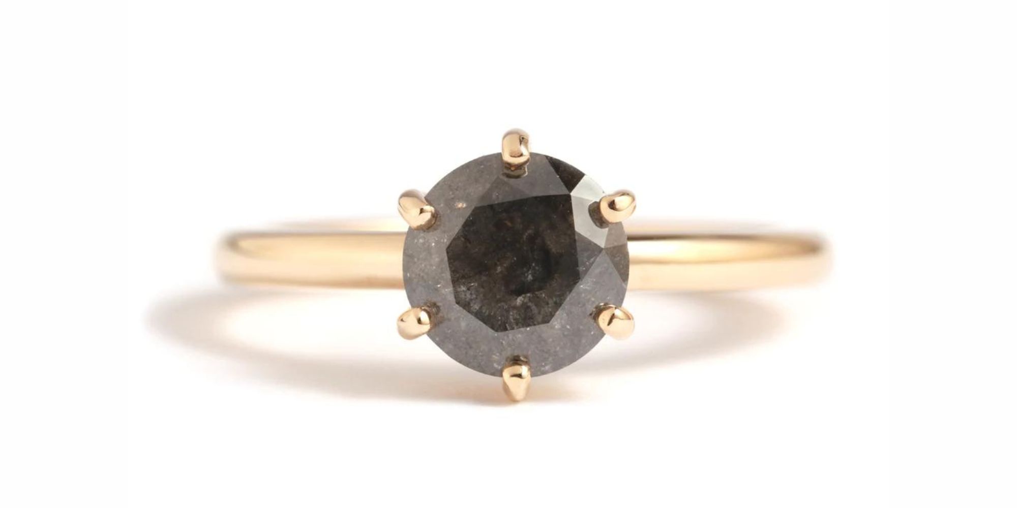 A round brilliant cut opaque grey diamond is held by prongs in this gold responsibly-made engagement ring by Melissa Joy Manning.