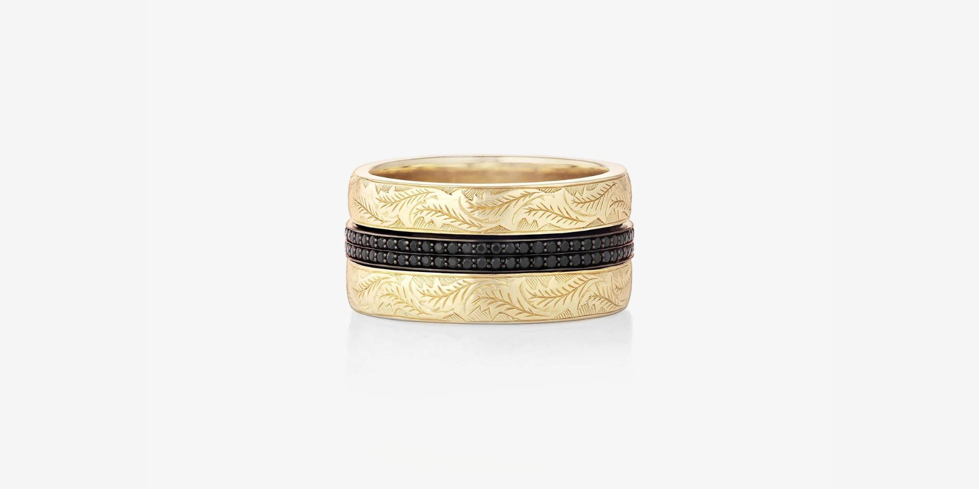 The 'Cigar Leaf Spinning Ring' crafted in 18ct yellow gold with hand engraved vine leaf detail and a continuous double row of black diamonds, made by Stephen Webster.