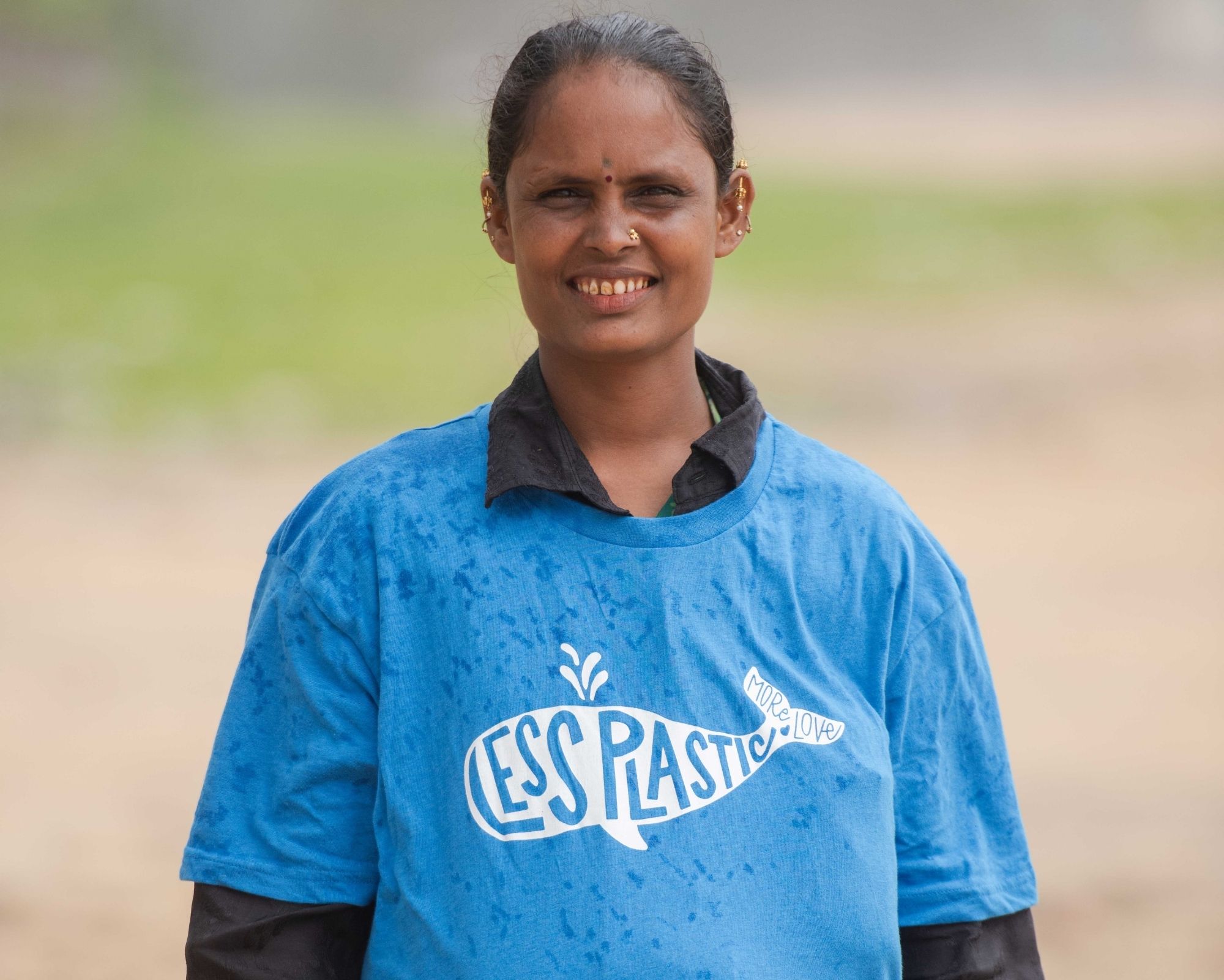 An Indian Plastics For Change workers wearing a blue Less Plastic More Love organic tee by Etiko.