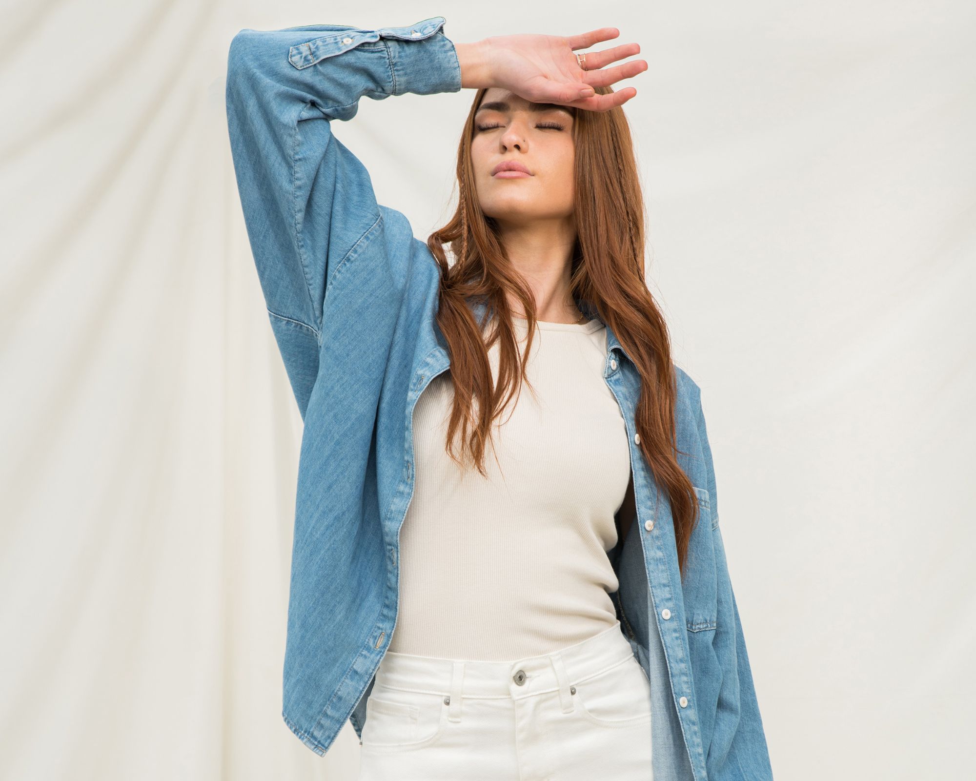 Someone wearing a sustainably made outfit by Outland Denim with a denim shirt, hemp singlet, and white denim jeans.