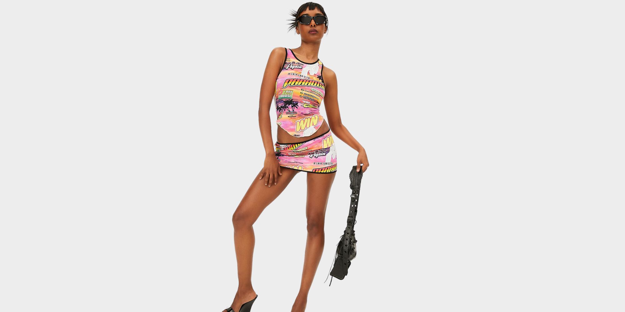 Someone wearing a colourful top and skirt combo with a black handbag and sunglasses by the brand MIAOU for LVRSustainable.