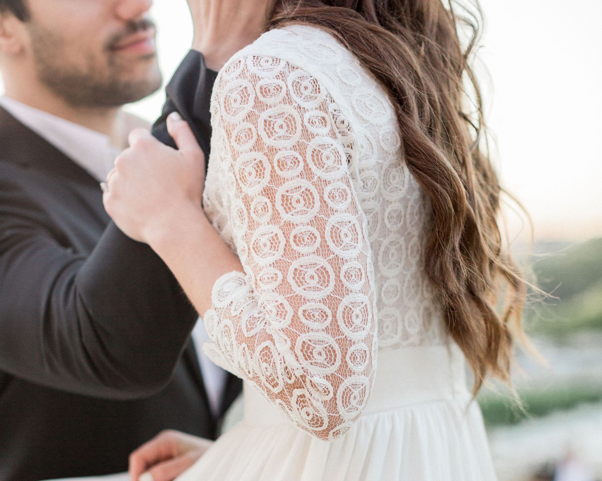 A bride and groom, the bride is wearing a white lacy custom made wedding dress by Dressarte Paris.