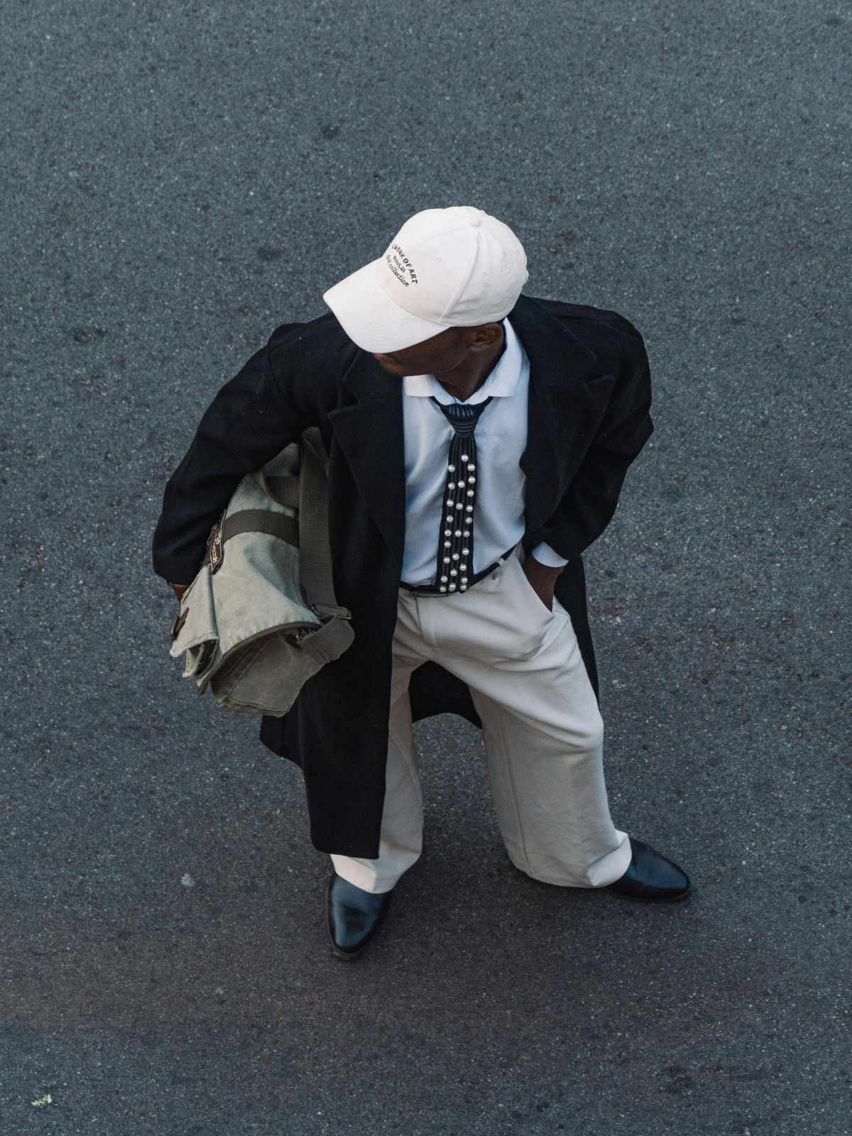 person standing in the street wearing minimalist outfit with black coat