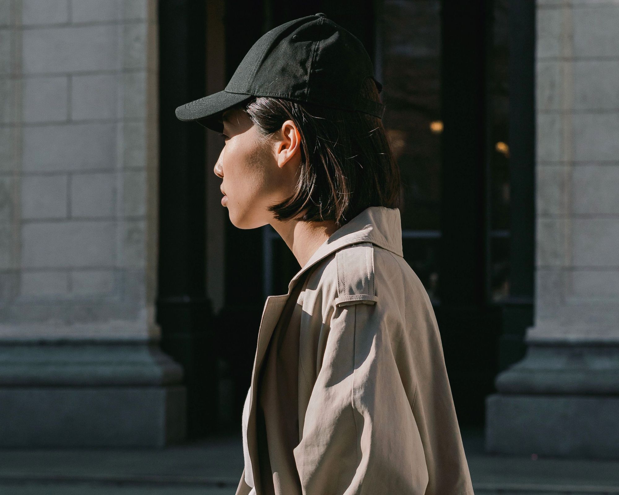 person wearing baseball cap and trench coat