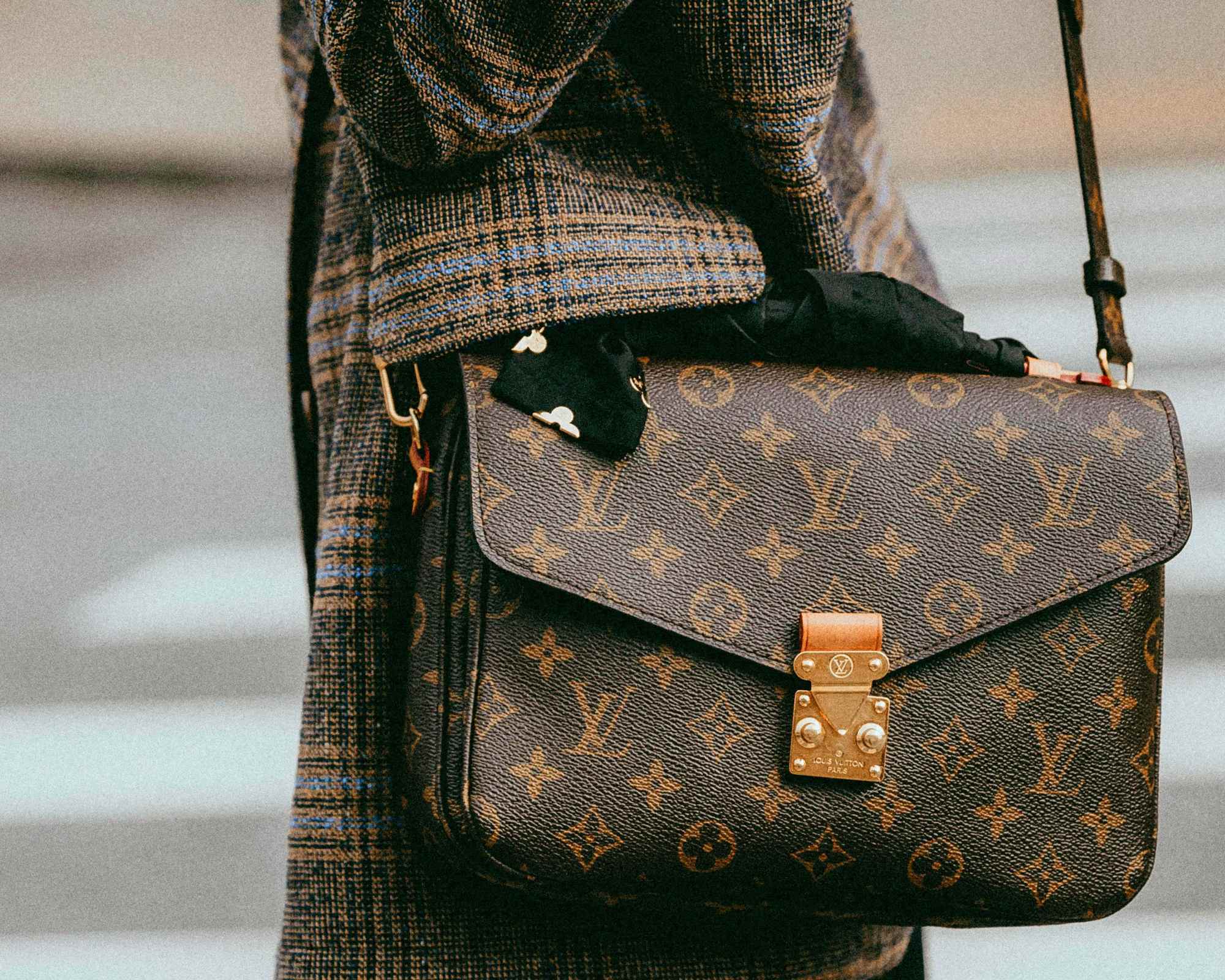 person wearing checked blazer and louis vuitton bag