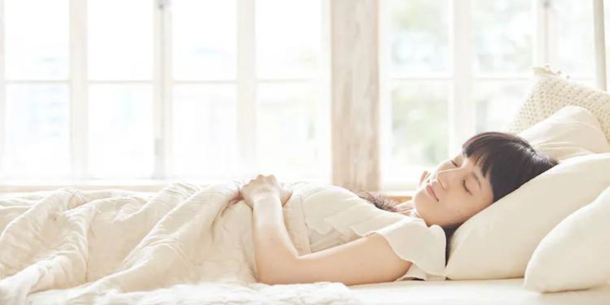 Someone sleeping in cream organic cotton bedding by PRISTINE.