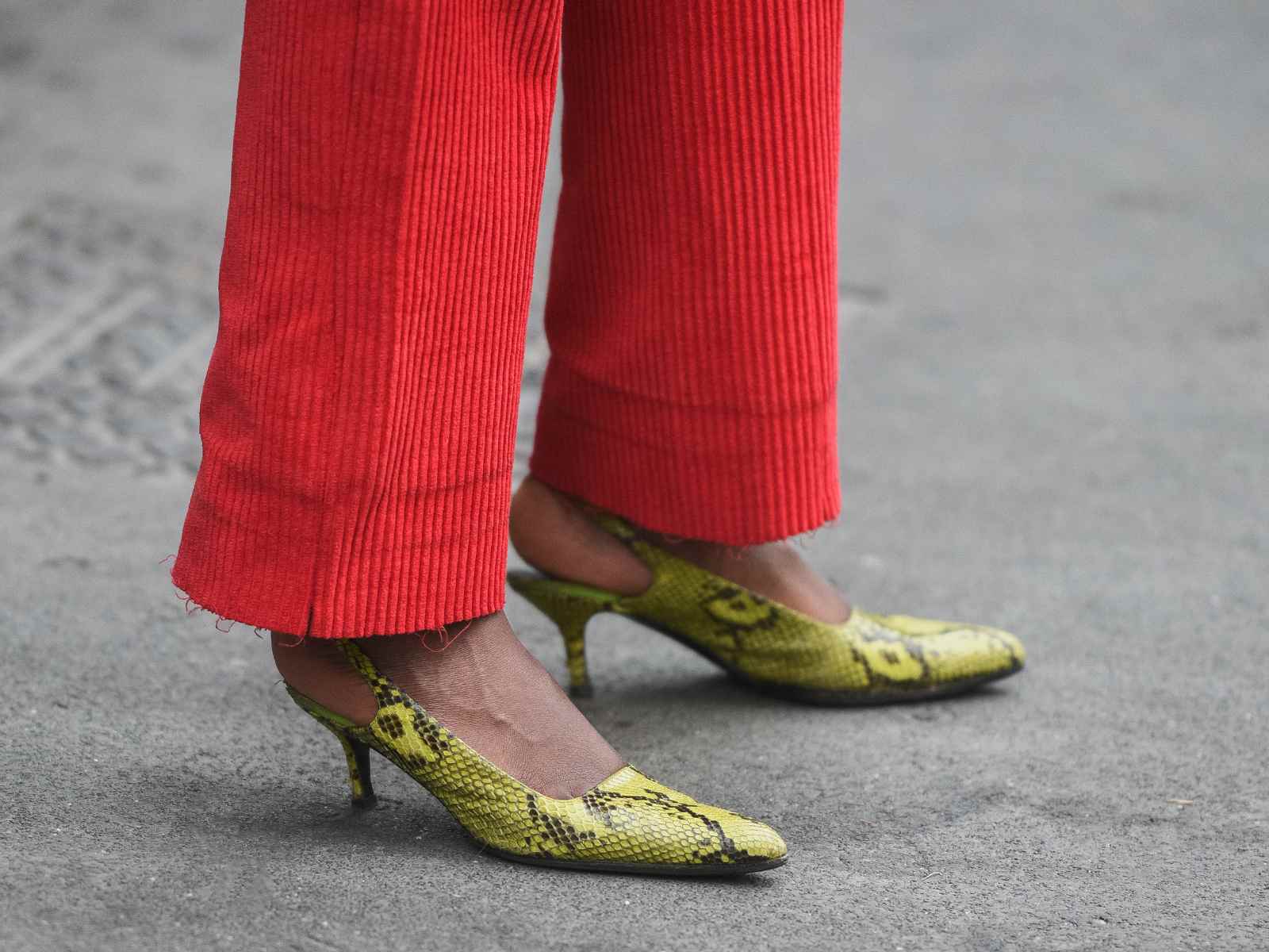 Person wearing yellow snakeskin shoes and red trousers