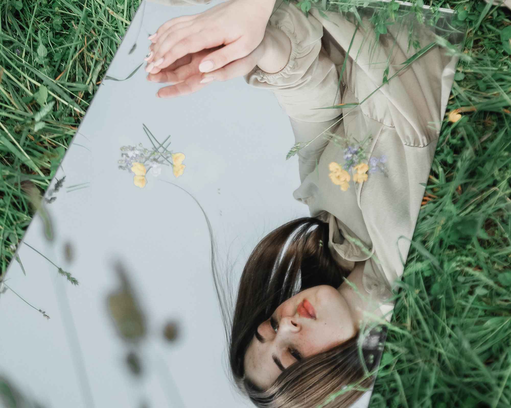 Person looking in a mirror in the grass