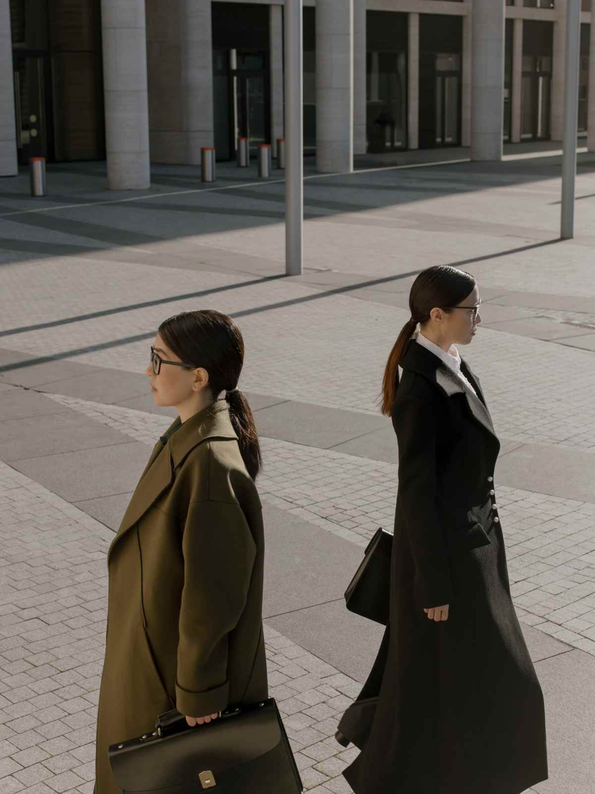 People wearing trench coats walking away from each other