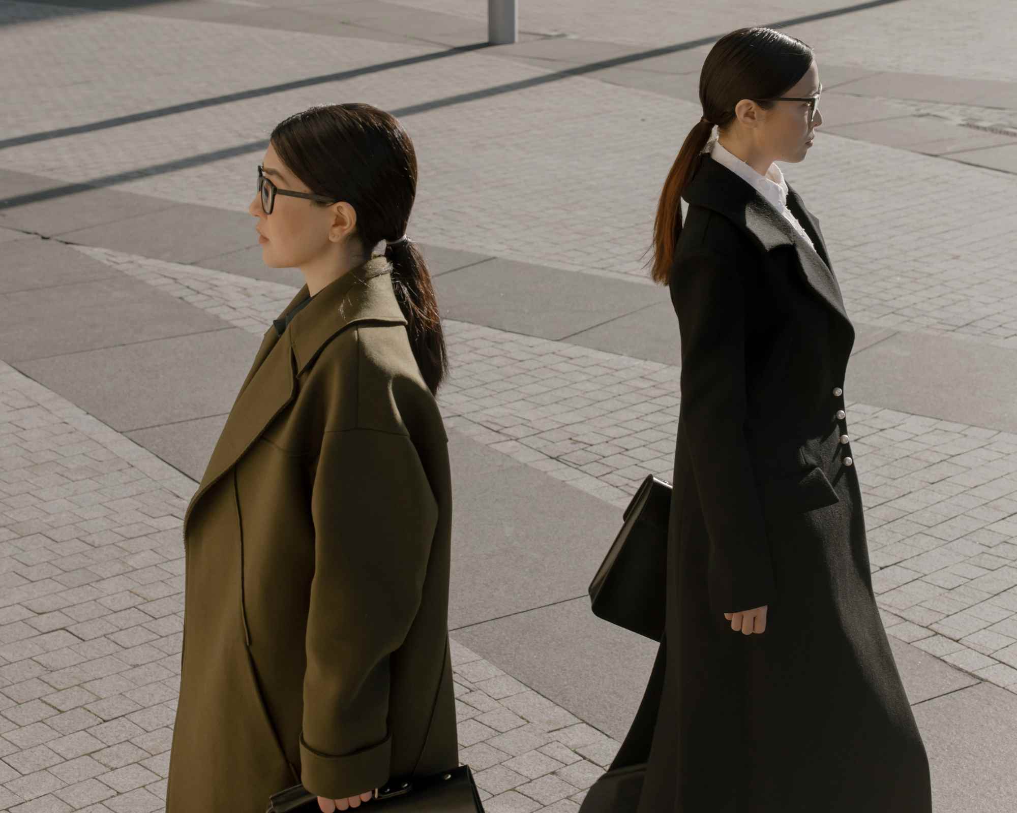 People wearing trench coats walking away from each other