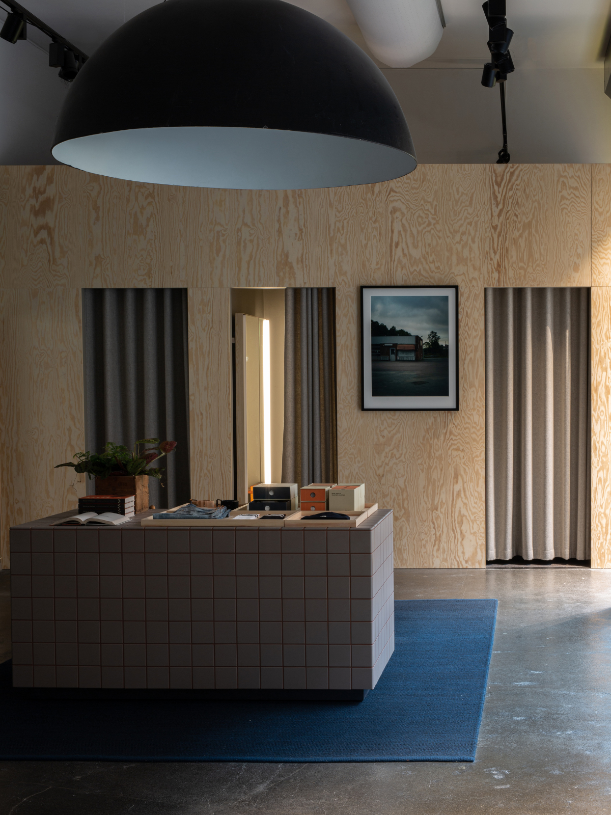 Nudie Jeans Repair Shop interior showing a calm and inviting interior space with natural wood, architectural lighting features, and items displayed inviting browsing