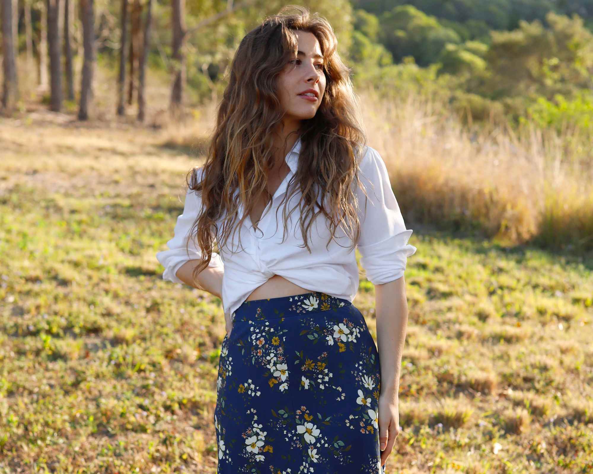 person wearing floral print skirt in a field